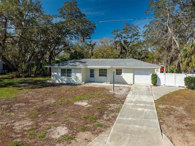 view of front facade featuring an attached garage, fence, concrete driveway, a gate, and stucco siding