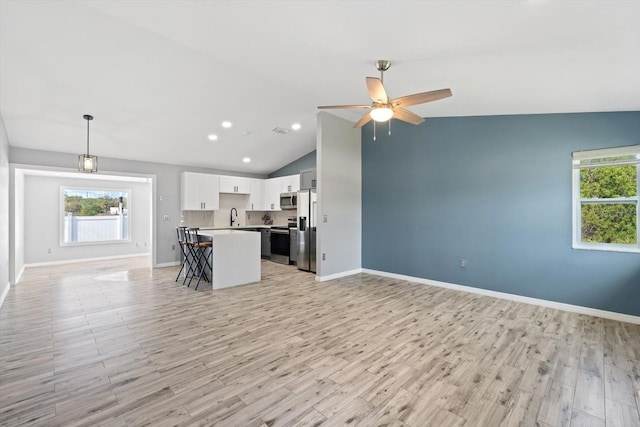 kitchen with open floor plan, light countertops, appliances with stainless steel finishes, a center island, and a kitchen bar