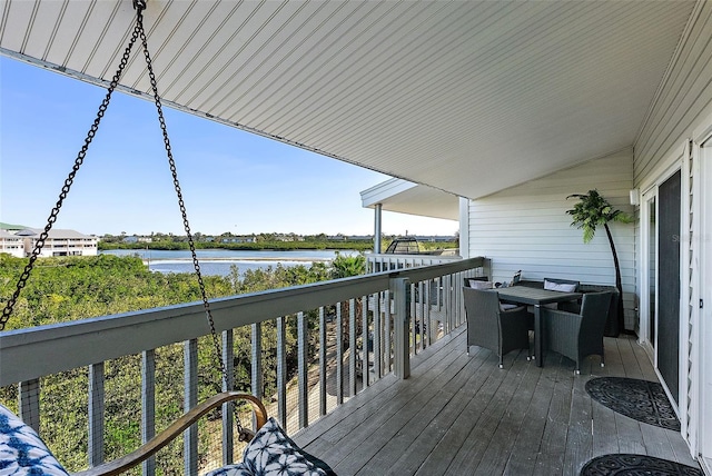 deck with outdoor dining area and a water view