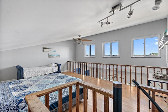 bedroom with lofted ceiling, track lighting, baseboards, and wood finished floors