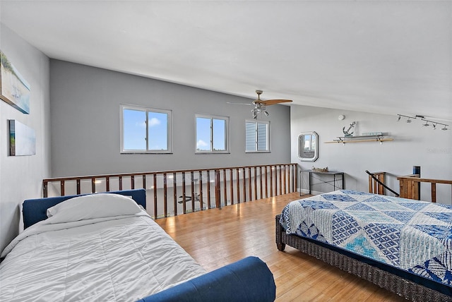 bedroom with light wood-type flooring, vaulted ceiling, and a ceiling fan