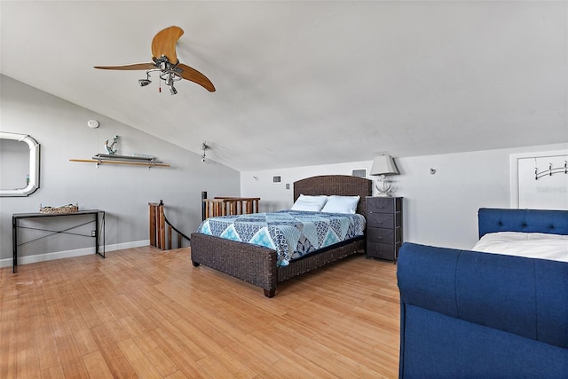 bedroom featuring a ceiling fan, vaulted ceiling, baseboards, and wood finished floors