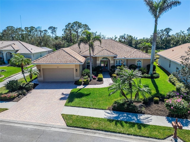 mediterranean / spanish home with decorative driveway, a front yard, an attached garage, and stucco siding