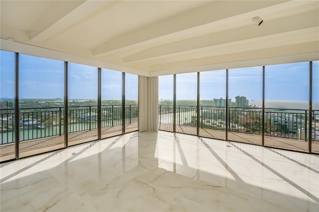 unfurnished sunroom featuring beamed ceiling, a water view, and a city view