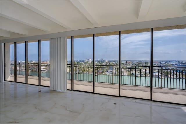 unfurnished sunroom with a water view, beam ceiling, and a city view