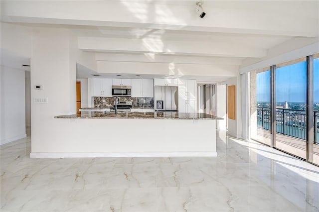 kitchen with marble finish floor, stainless steel appliances, decorative backsplash, white cabinetry, and dark stone countertops