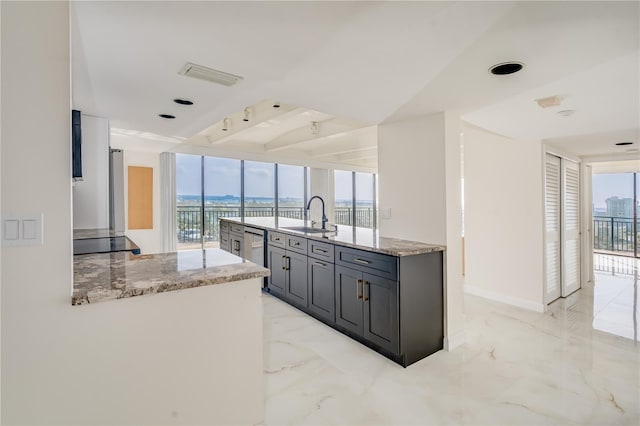 kitchen with marble finish floor, a sink, and light stone countertops