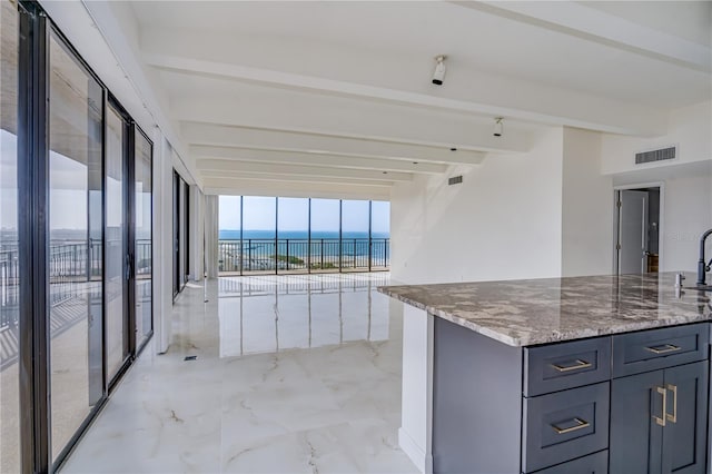 kitchen featuring light stone counters, a water view, visible vents, marble finish floor, and beamed ceiling