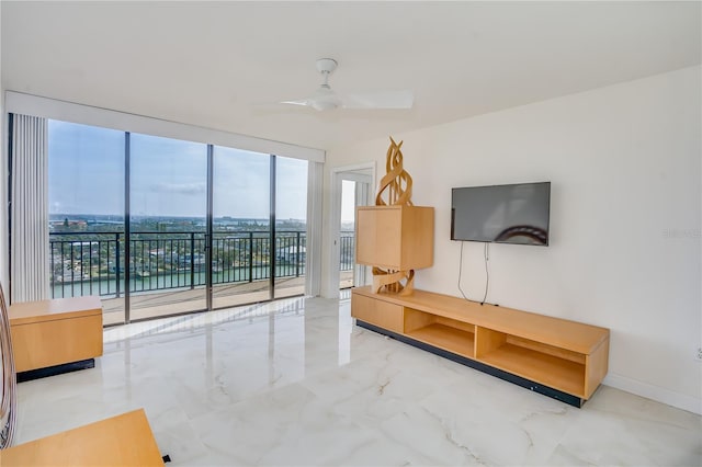 living area featuring a wall of windows, marble finish floor, ceiling fan, and baseboards