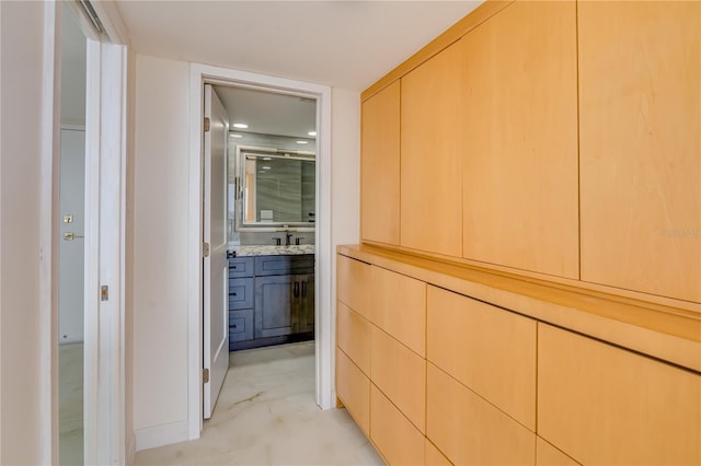 hallway featuring marble finish floor and a sink