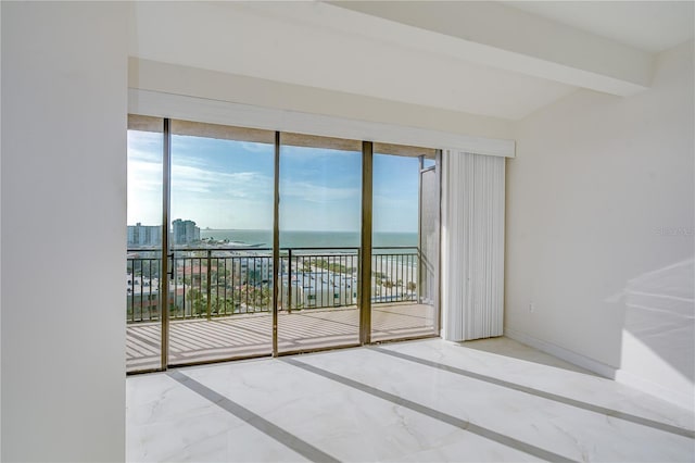 spare room featuring marble finish floor, a water view, a city view, and baseboards