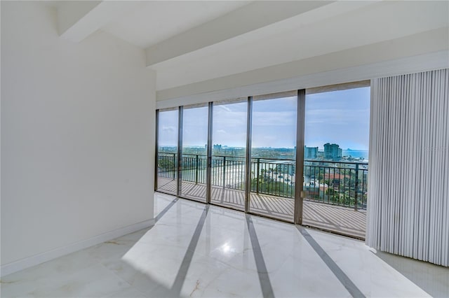 unfurnished room featuring marble finish floor, a view of city, baseboards, and beamed ceiling