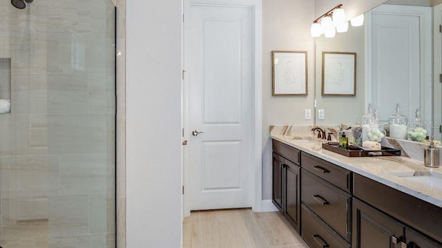 full bath with double vanity, a tile shower, and a sink