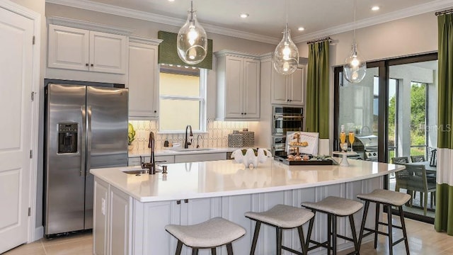 kitchen with appliances with stainless steel finishes, light countertops, a large island, and white cabinetry