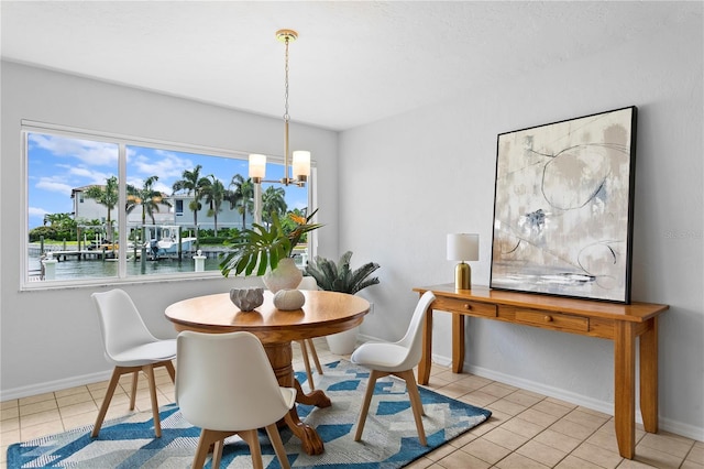 dining area with light tile patterned floors, a water view, baseboards, and a notable chandelier