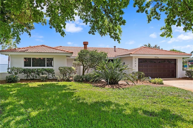 view of front of property with a garage, driveway, a tile roof, a front lawn, and stucco siding