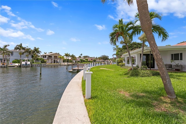 view of dock featuring a yard, a water view, and a residential view