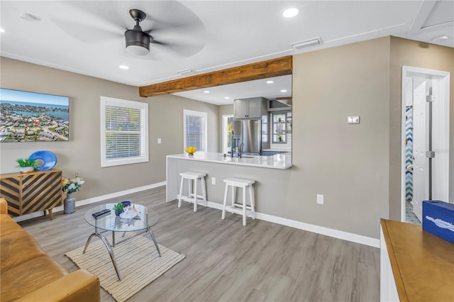 living area with baseboards, visible vents, light wood-style floors, and recessed lighting