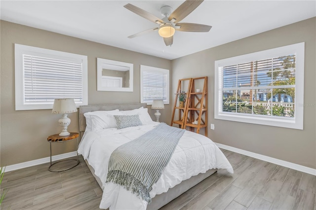 bedroom featuring ceiling fan, light wood-style flooring, and baseboards