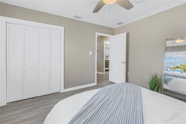 bedroom featuring visible vents, wood finished floors, a ceiling fan, and a closet
