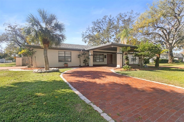 view of front of house with a front yard, decorative driveway, and stucco siding