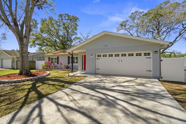 ranch-style home with an attached garage, driveway, fence, and stucco siding