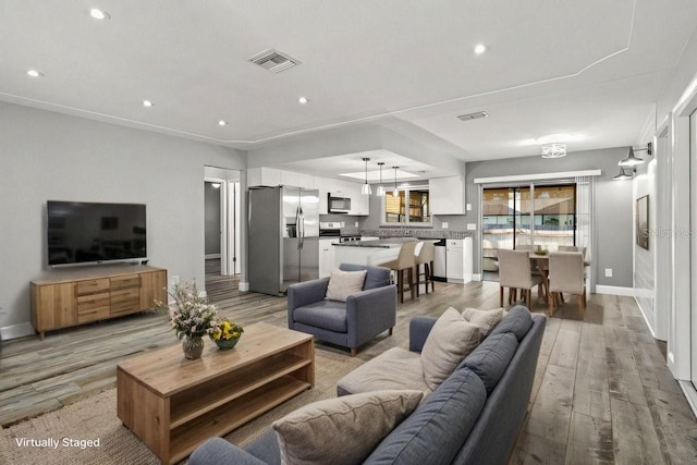 living room featuring recessed lighting, visible vents, baseboards, and wood finished floors