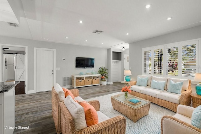 living area featuring a barn door, visible vents, wood finished floors, and recessed lighting