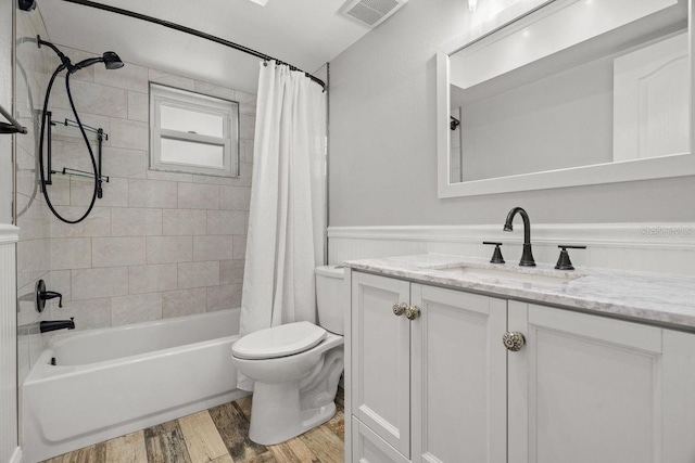 full bath featuring a wainscoted wall, visible vents, shower / bathtub combination with curtain, vanity, and wood finished floors