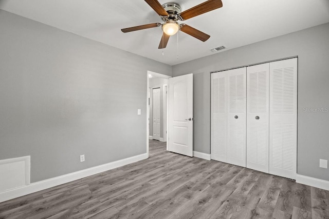 unfurnished bedroom with light wood finished floors, baseboards, visible vents, and a closet