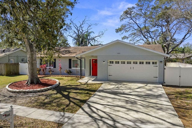 ranch-style home with a garage, fence, concrete driveway, stucco siding, and a front yard