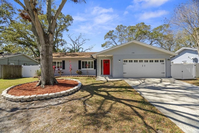 single story home featuring an attached garage, fence, a gate, stucco siding, and a front lawn