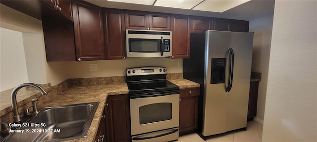 kitchen featuring light tile patterned floors, dark brown cabinets, appliances with stainless steel finishes, and a sink