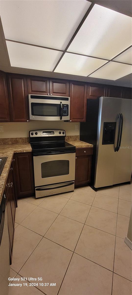 kitchen with light tile patterned floors, stainless steel appliances, and dark brown cabinetry