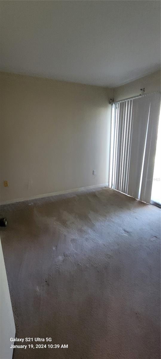 carpeted spare room featuring baseboards