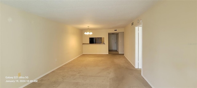 empty room with light carpet, baseboards, visible vents, and a chandelier