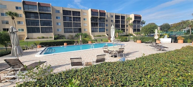 pool with a patio area and fence