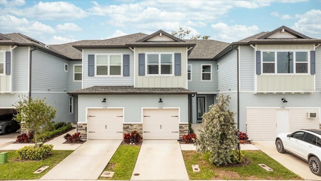 multi unit property with a shingled roof, board and batten siding, a garage, stone siding, and driveway