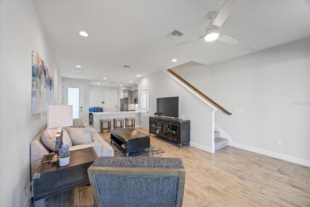 living room with recessed lighting, visible vents, light wood-style flooring, stairway, and baseboards