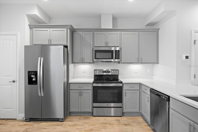 kitchen with light countertops, appliances with stainless steel finishes, light wood-style floors, and gray cabinetry