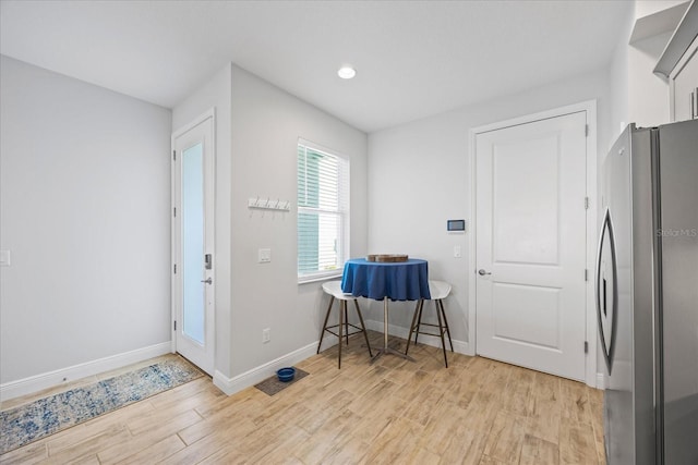 interior space with freestanding refrigerator, light wood-style flooring, and baseboards