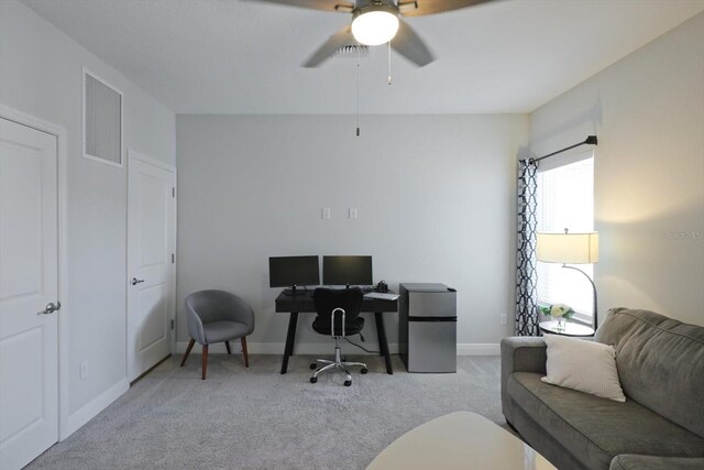 office featuring light colored carpet, ceiling fan, visible vents, and baseboards