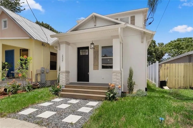 view of front facade featuring covered porch, fence, and stucco siding