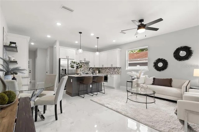 living area featuring recessed lighting, marble finish floor, visible vents, and ceiling fan