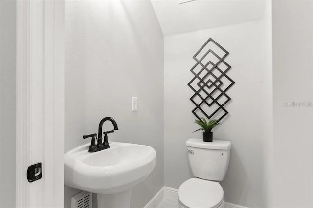 bathroom featuring toilet, baseboards, and a sink