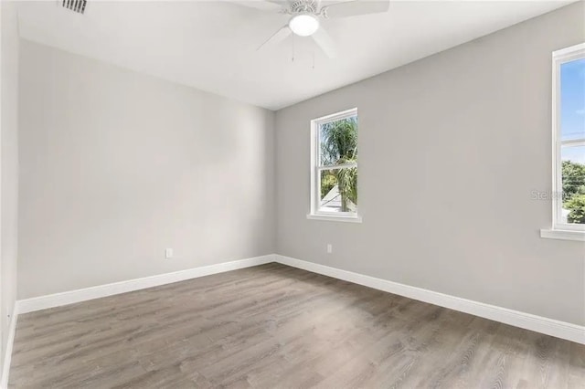 unfurnished room featuring a ceiling fan, visible vents, baseboards, and wood finished floors