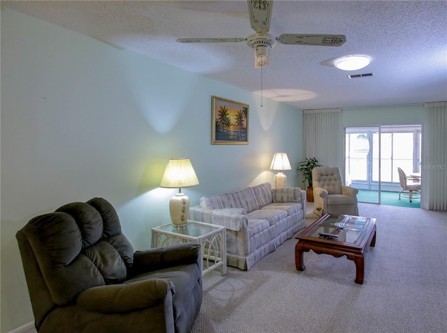 carpeted living area featuring a textured ceiling, visible vents, and a ceiling fan