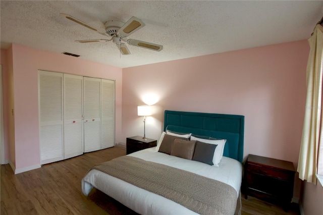 bedroom with a closet, visible vents, a ceiling fan, a textured ceiling, and wood finished floors