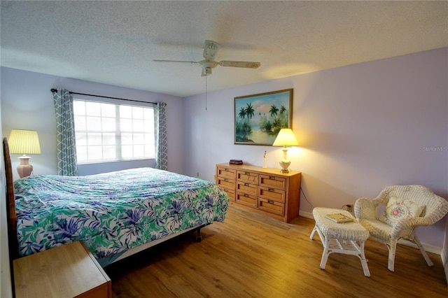 bedroom with baseboards, ceiling fan, a textured ceiling, and light wood finished floors