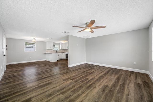 unfurnished living room with dark wood-type flooring, visible vents, baseboards, and a ceiling fan